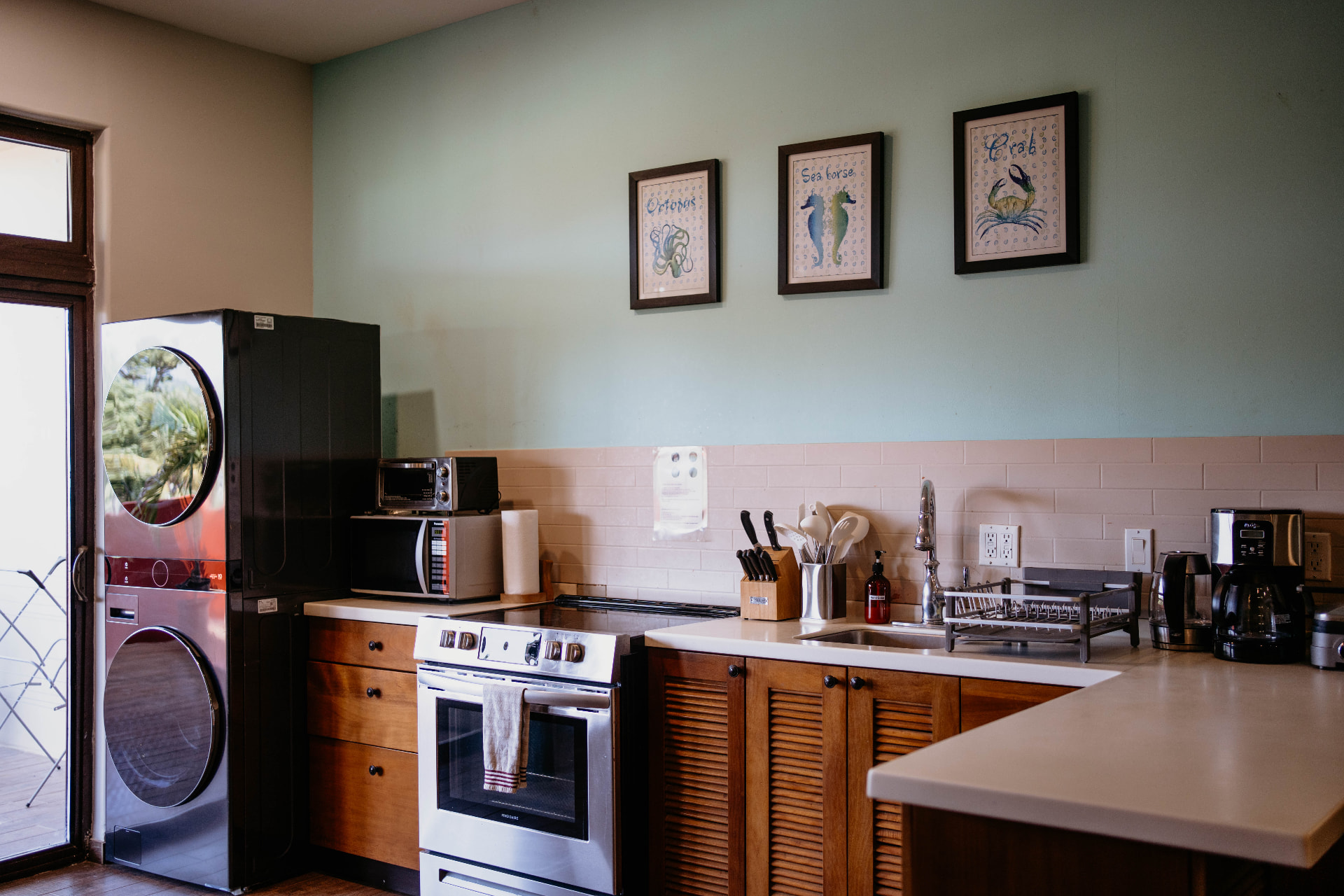Apartment B21 — kitchen with wooden cabinetry and framed sea prints