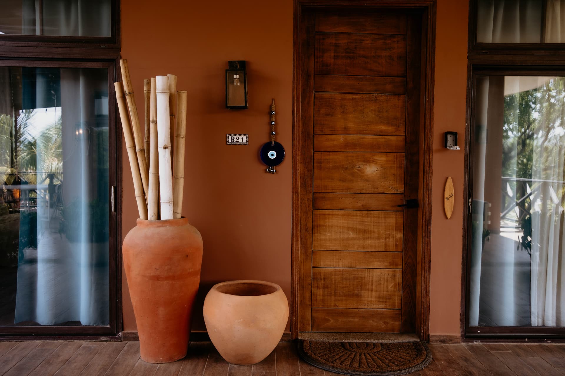 Apartment B21 — entrance with the B21 tile, wooden door and terracotta pots