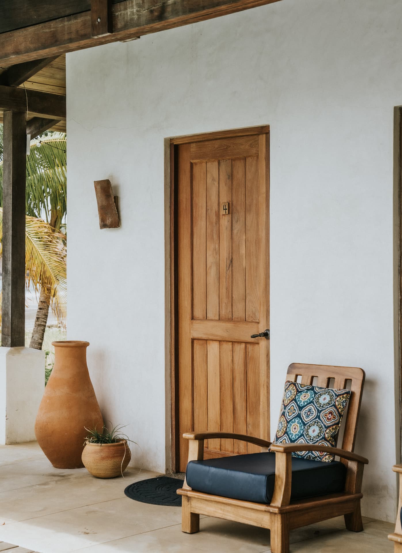 Villa Nomada — covered terrace with wooden door and terracotta pots