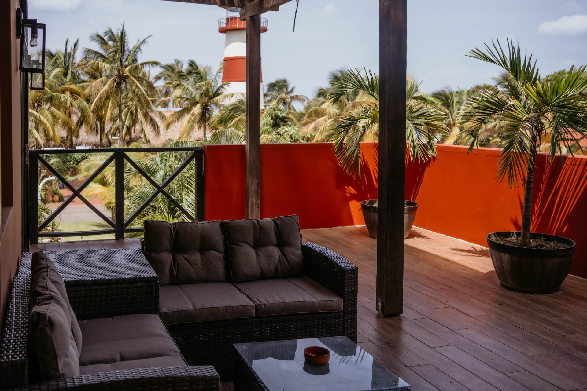 Apartment B21 — covered balcony with wicker lounge seating and palms