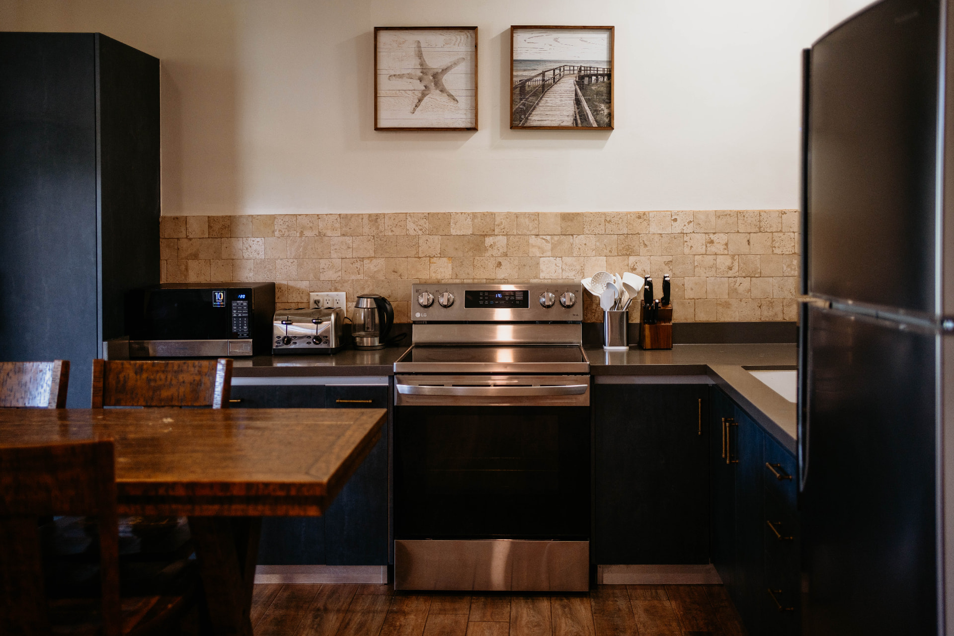 Apartment A18 — kitchen with dark cabinetry, stone backsplash and wooden table