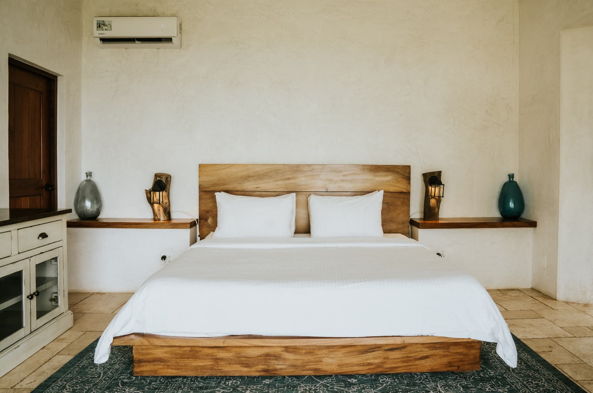 Villa Nomada — master bed centred between built-in shelves and lantern lamps