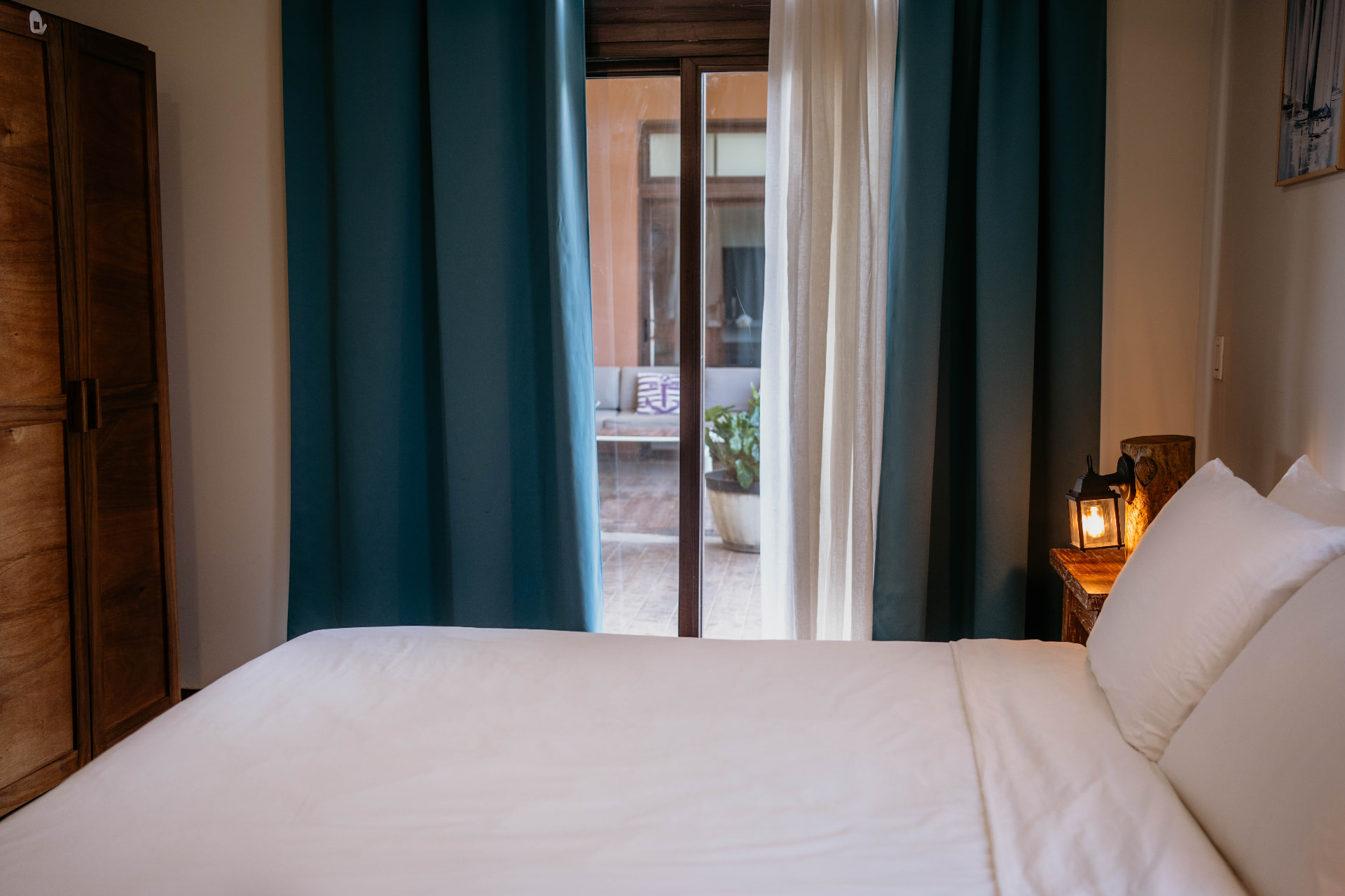 Apartment B21 — bedroom with teal curtains opening onto the terrace