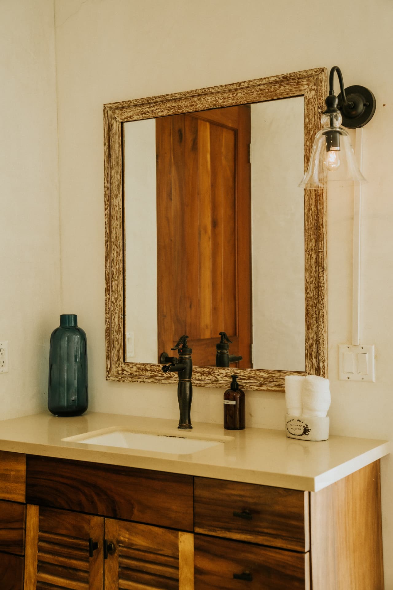 Villa Nomada — en-suite vanity with timber-framed mirror and brass tap