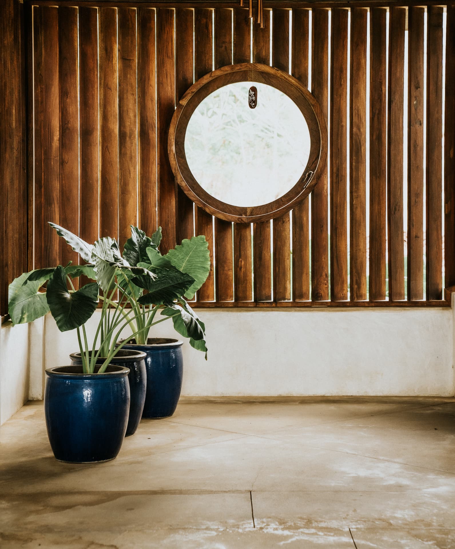 Villa Nomada — round wooden mirror, timber screen and blue glazed pots