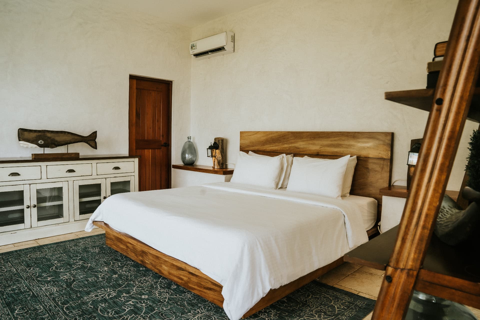Villa Nomada — master bedroom with wooden headboard and carved whale on the dresser
