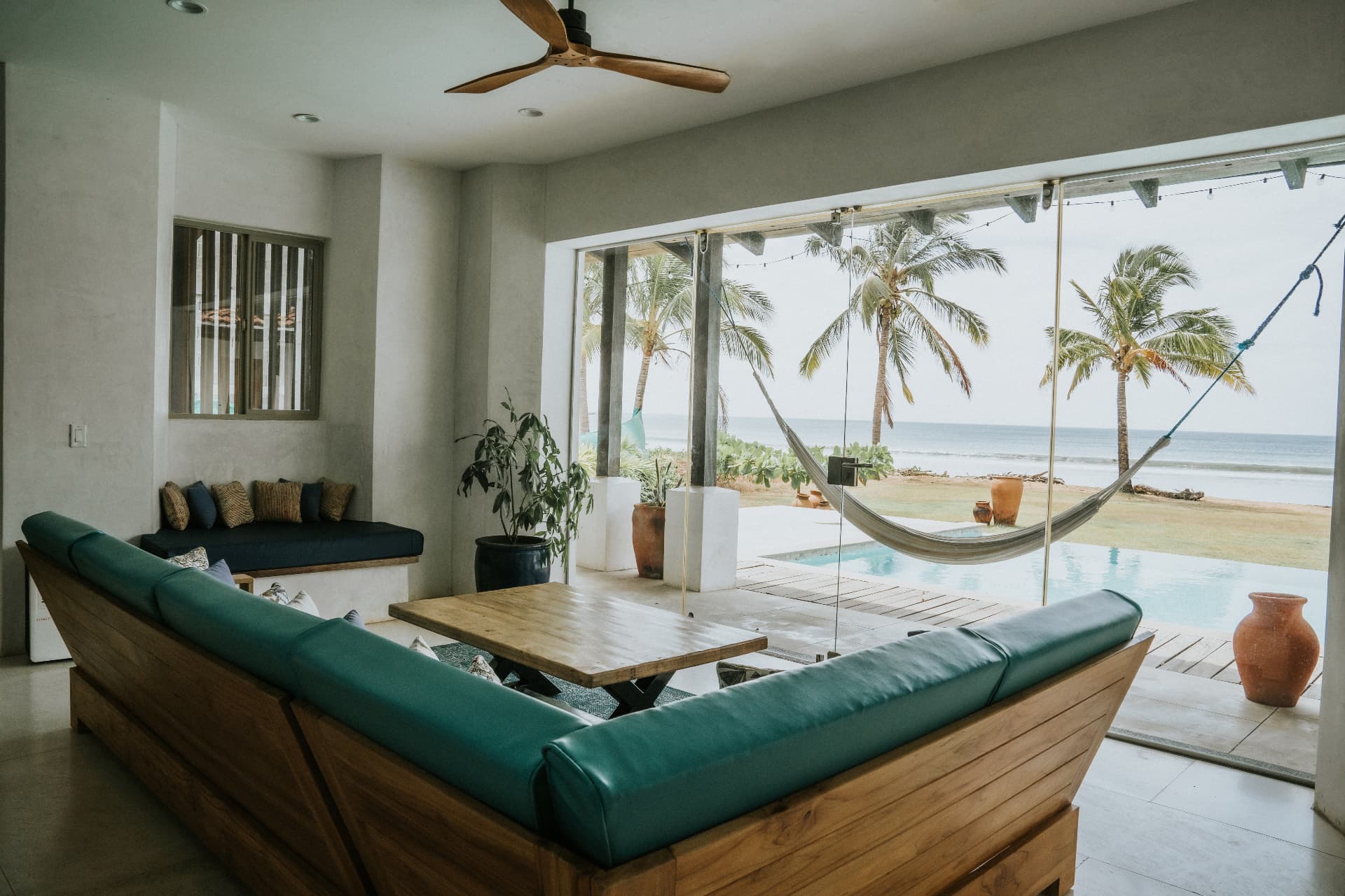 Villa Nomada — living room opening to the pool, palms and the beach beyond