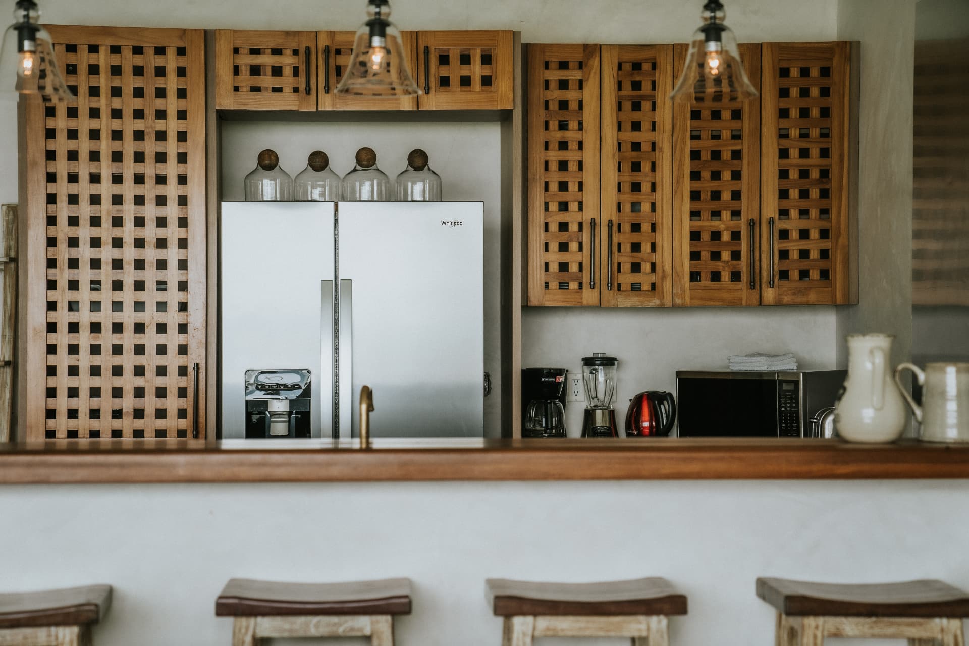 Villa Nomada — kitchen seen across the breakfast bar, teak lattice cabinetry